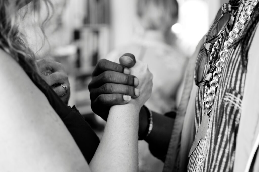 Faithfully examining the intersection of white supremacy and Christian nationalism A white person and a Black person are shown facing each other and clasping hands at chest level.