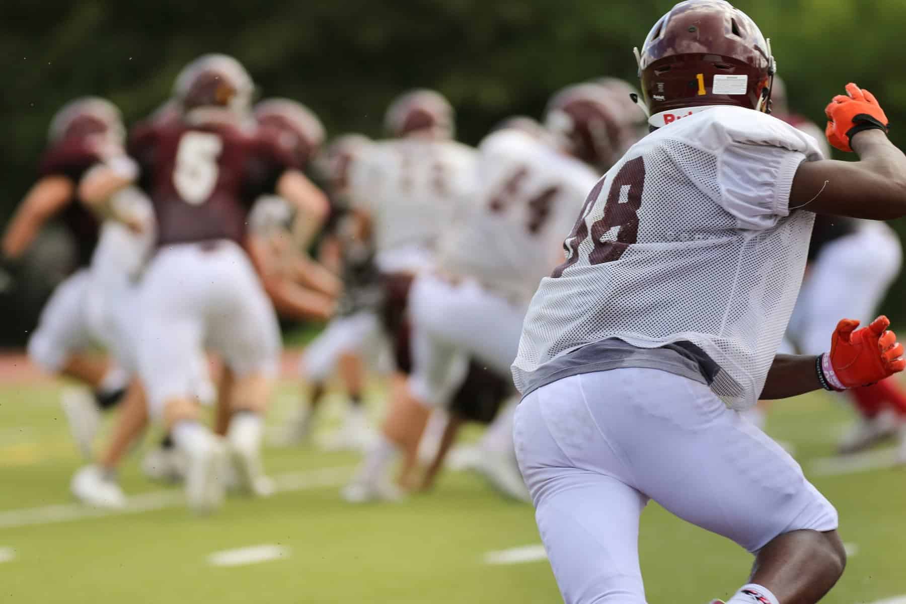 Youth football players wearing maroon and white are shown in abstract.