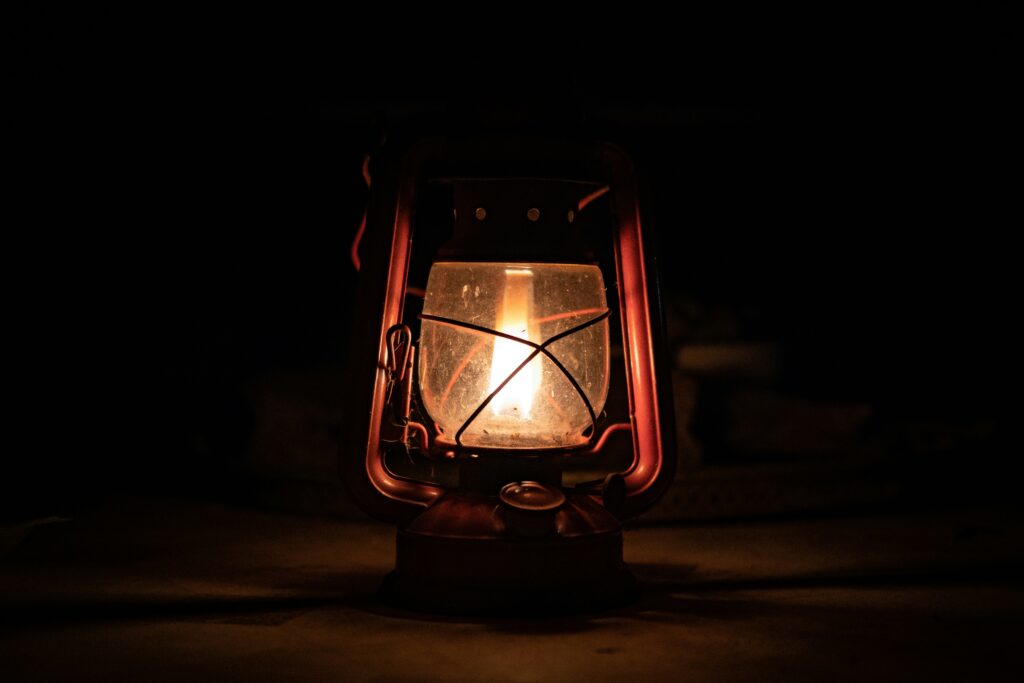 A single lit gas lantern sits by itself in the dark.