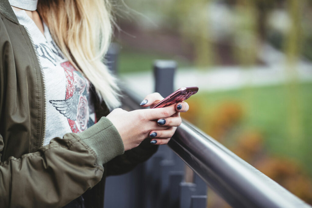 Use the Hallow app? You may want to reconsider I woman stands outside holding her phone.