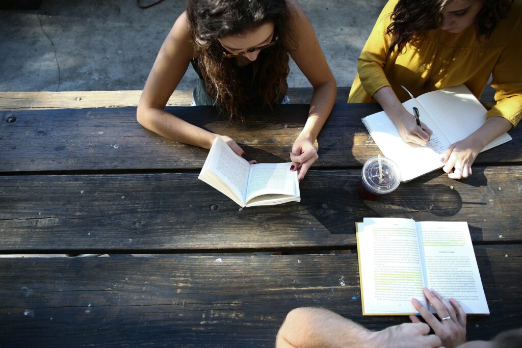 Young women sitting at a table with books.