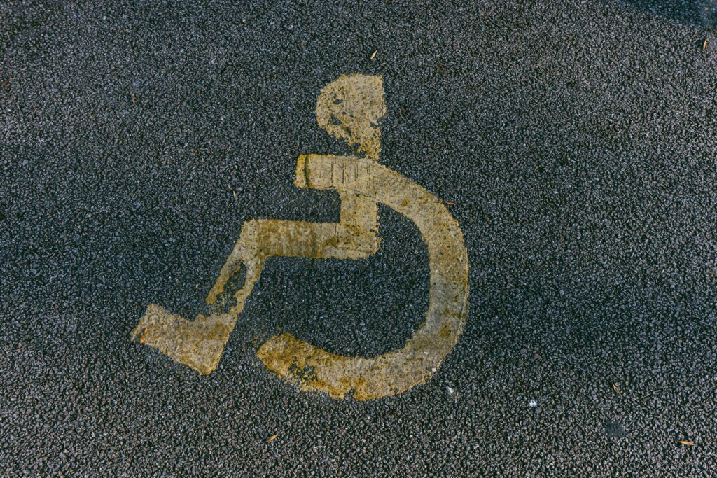 From unawareness to inclusion: Transforming church culture for people with disabilities Worn yellow handicap symbol painted on asphalt.