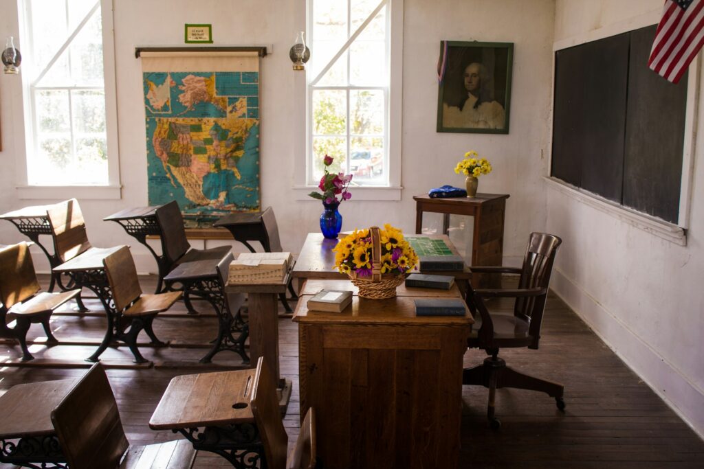 School Vouchers: Examining the impact on private and public schools A historic classroom as seen from the side with student and a teacher's desk.