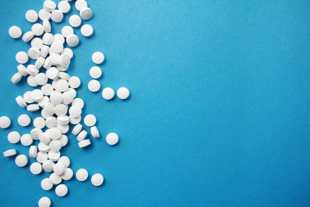 A group of round white pills in a line on the left of a blue background.