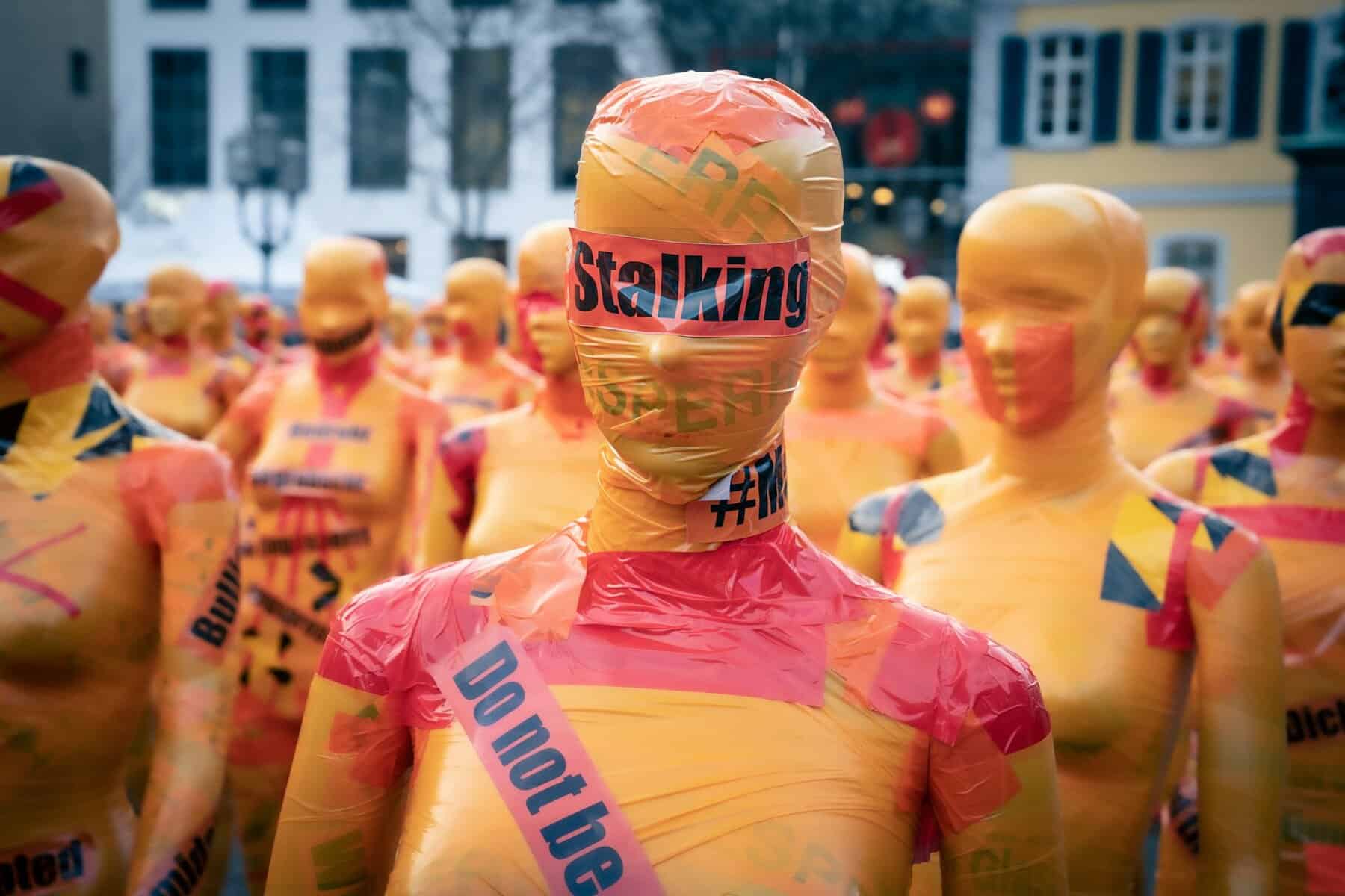 Yellow mannequins wrapped in red tape.