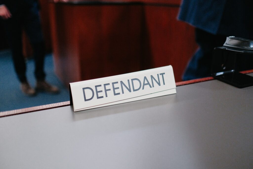 A sign on a desk says "Defendant".