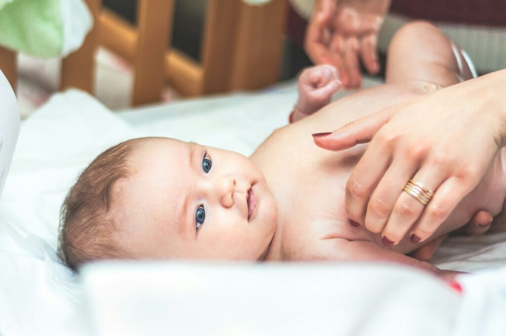 Proxy voting for parents stalls Congress, ends in controversial compromise An infant lays on it's back with a woman's hands over it.