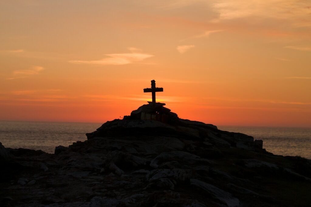 A rock pile with a cross on top at sunset.