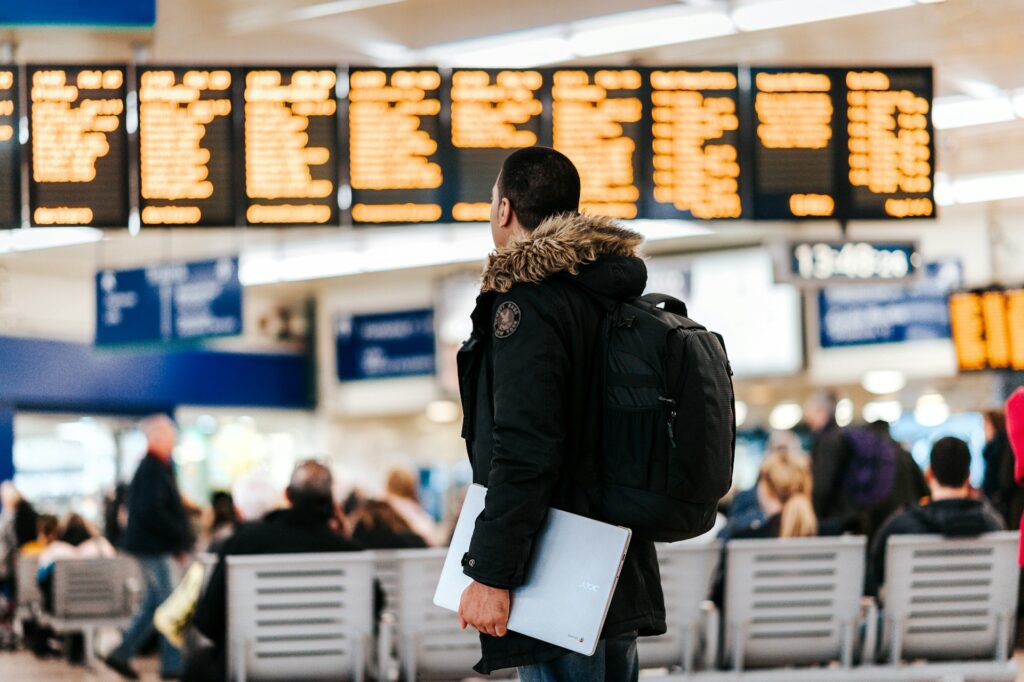 Man in airport looking at flight LED screens.