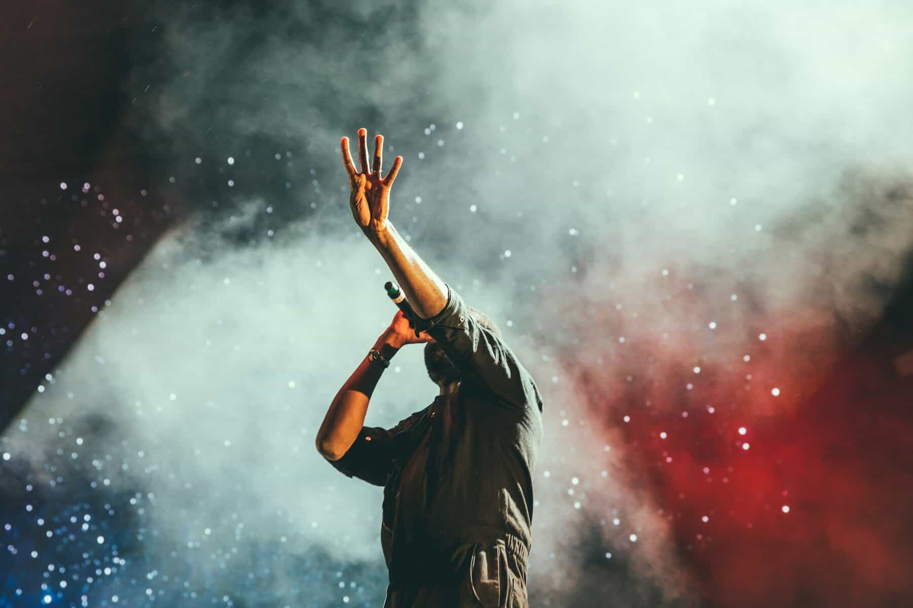 A male singer holding a microphone in stage fog.