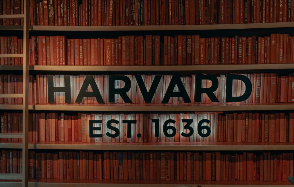 the words Harvard 1636 in front of shelved library books.