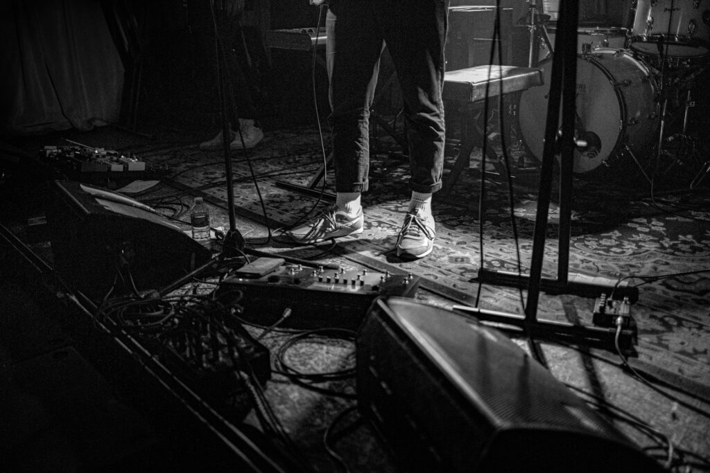 Newsboys vs. Faith Live: Inside the canceled 2025 tour drama Black and white image of a man's feet on stage by drums and a microphone.