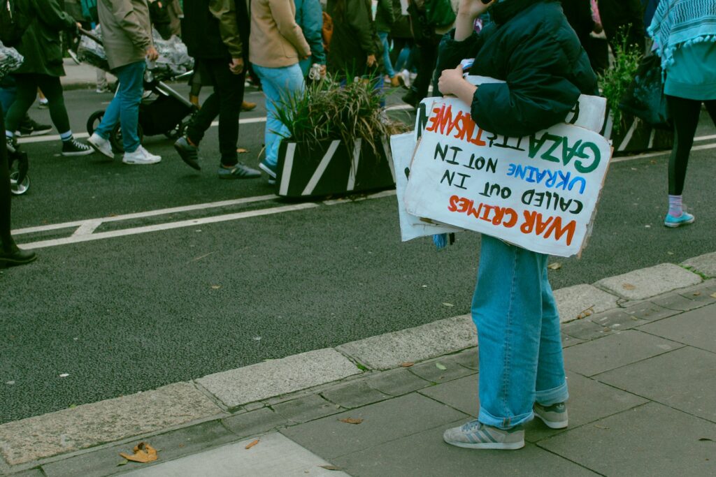 NGOs decry new Israeli restrictions on Palestinian aid operations A person holds a humanitarian protest sign under their arm.