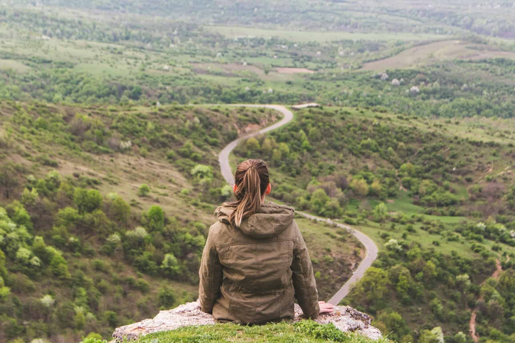 A woman sits on a rock with back to the camera in Arad, Romania.