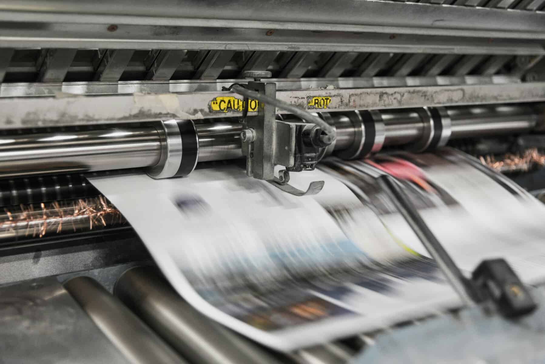 Newspaper being printed quickly on a printing press.