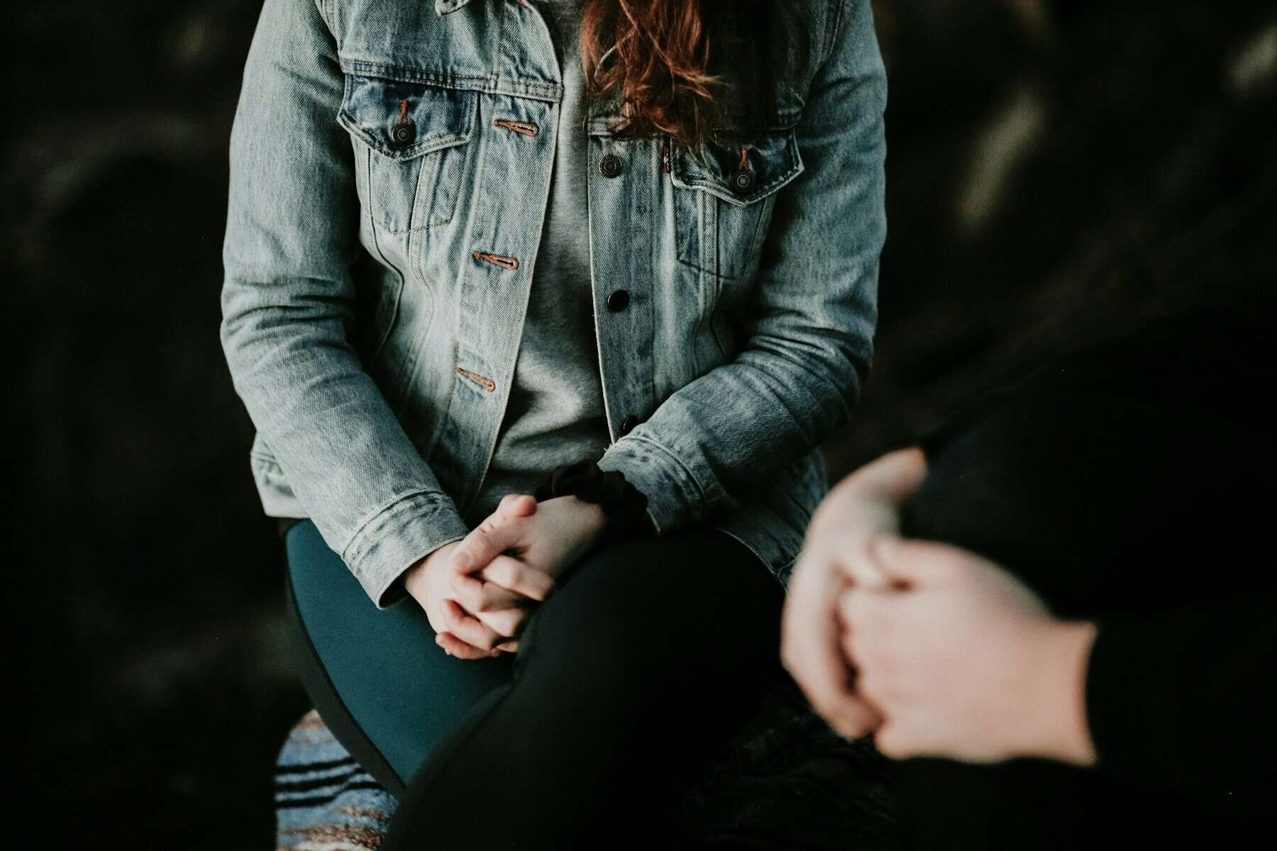 A man and woman's hands clasped in their laps.