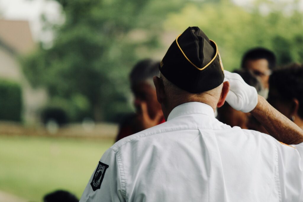An older man seen saluting from behind.