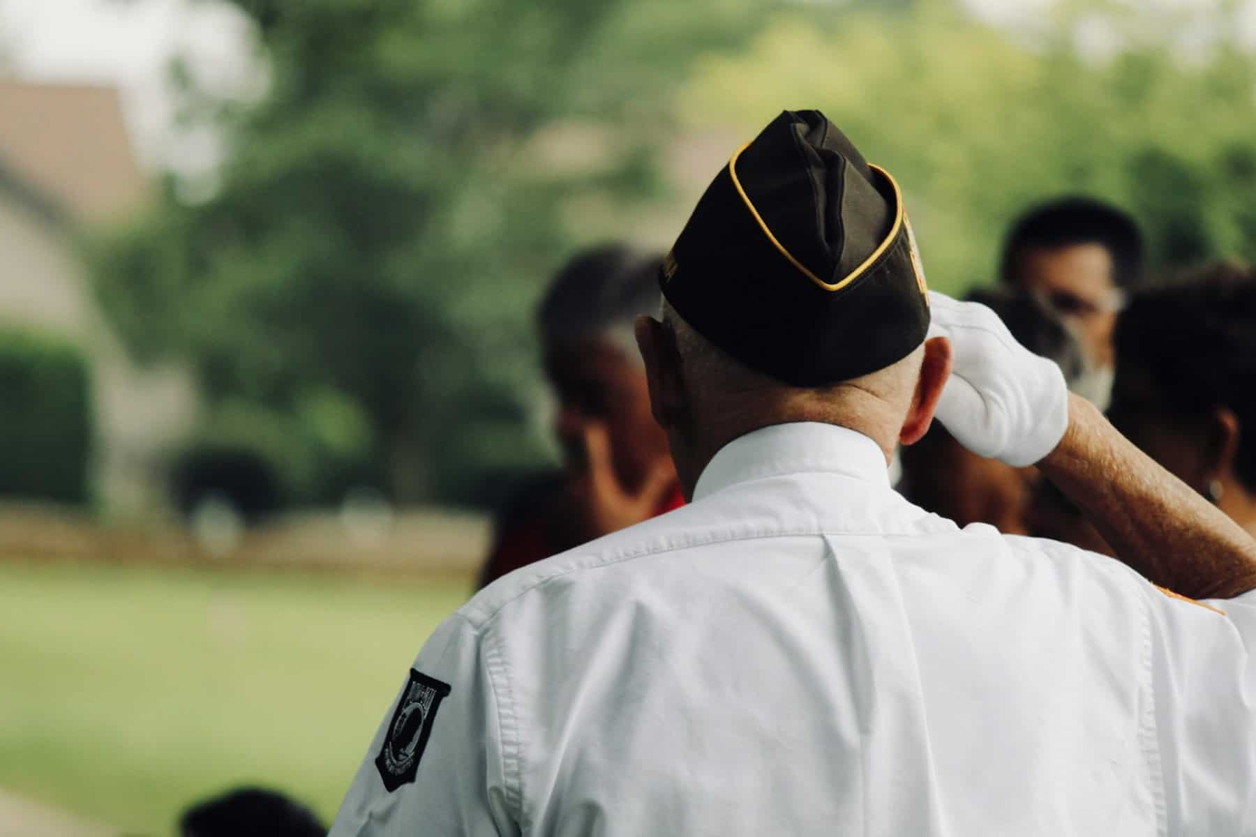 An older man seen saluting from behind.