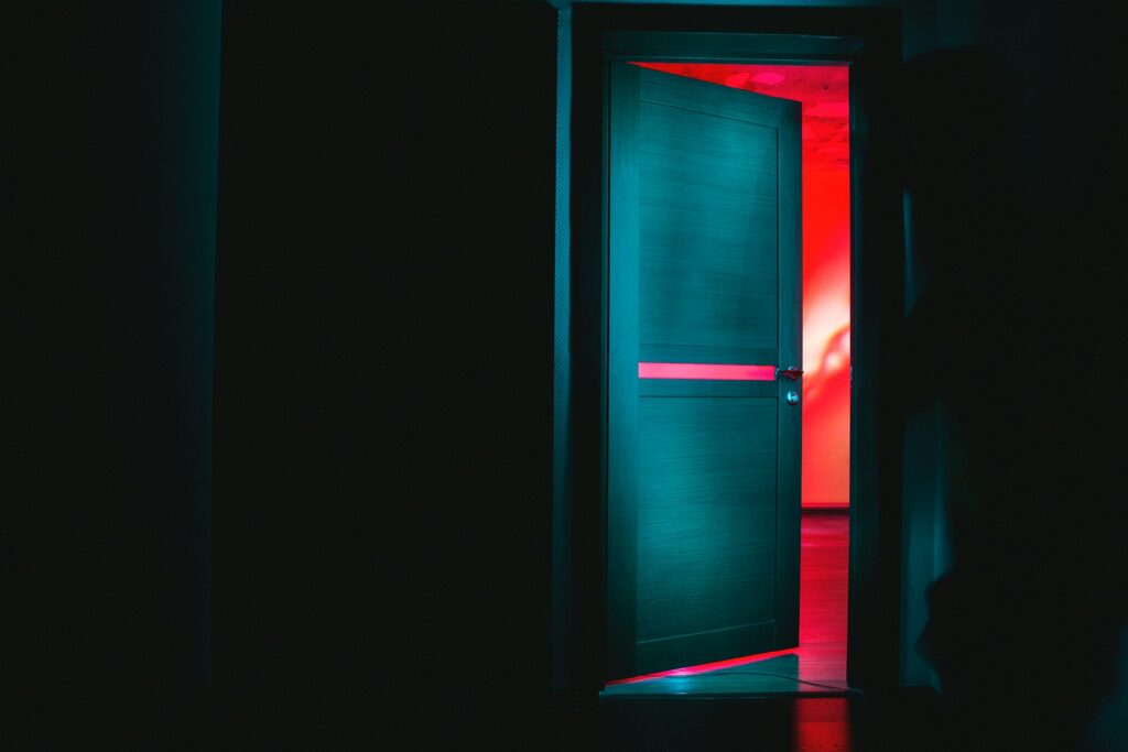 A green door opening into a red lit room.