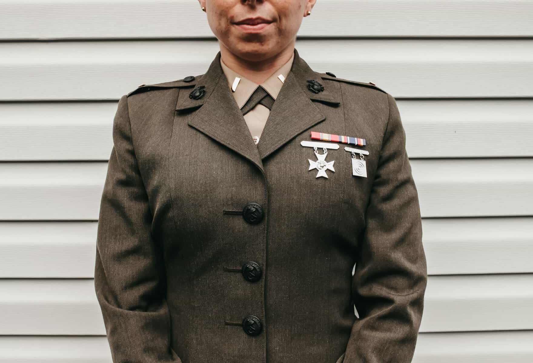 A woman in a military uniform from the nose to elbows.