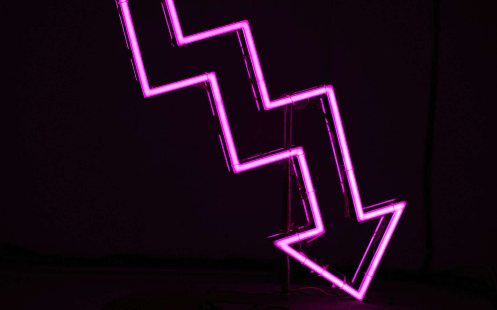 A pink neon sign with a jagged down arrow.