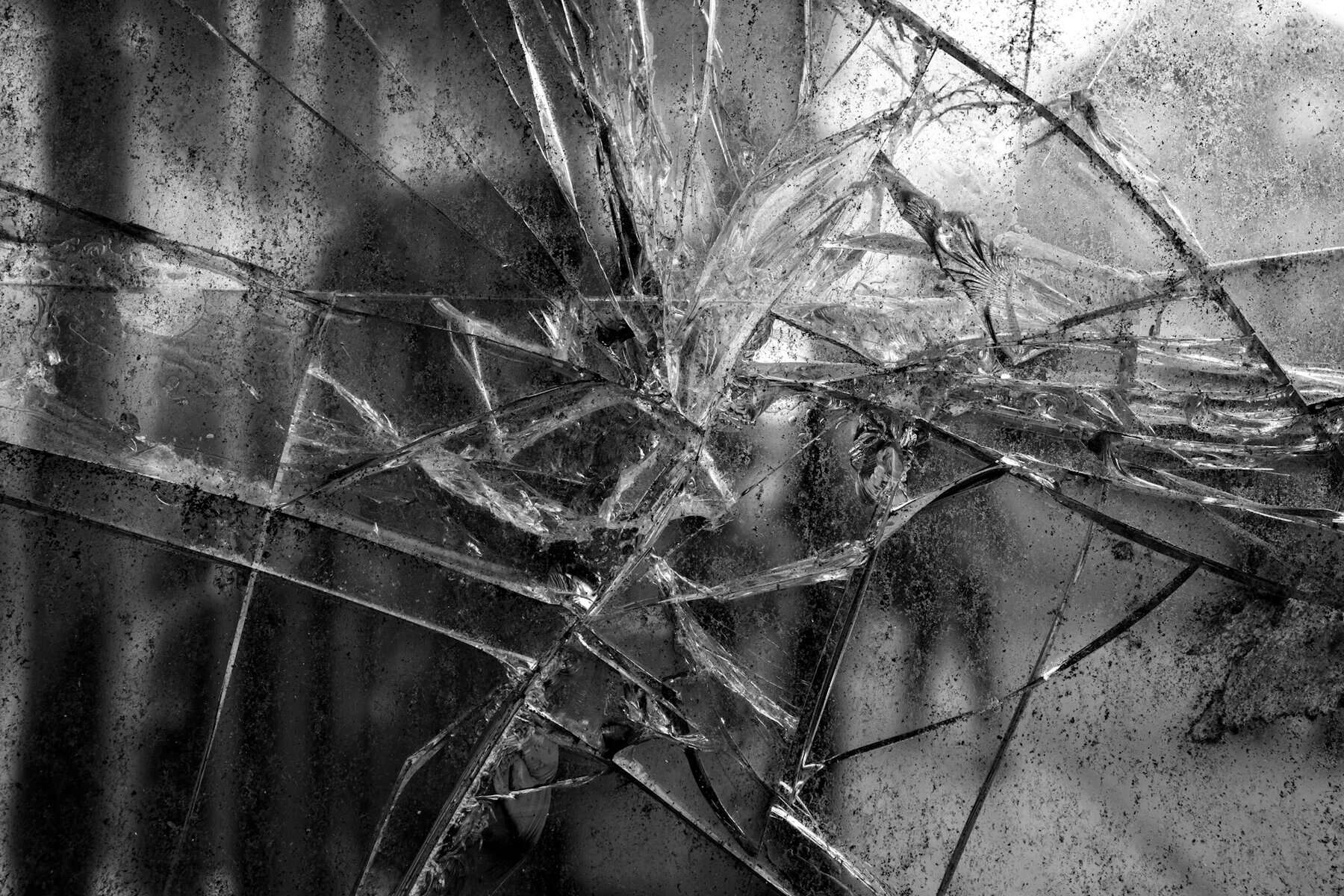 Black and white grungy photo of a badly fractured mirror.