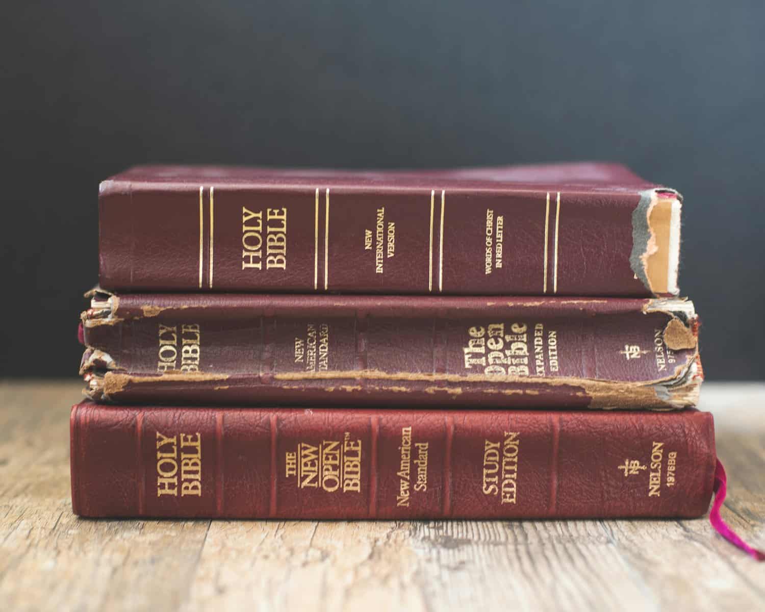 A stack of three worn brown Bibles.
