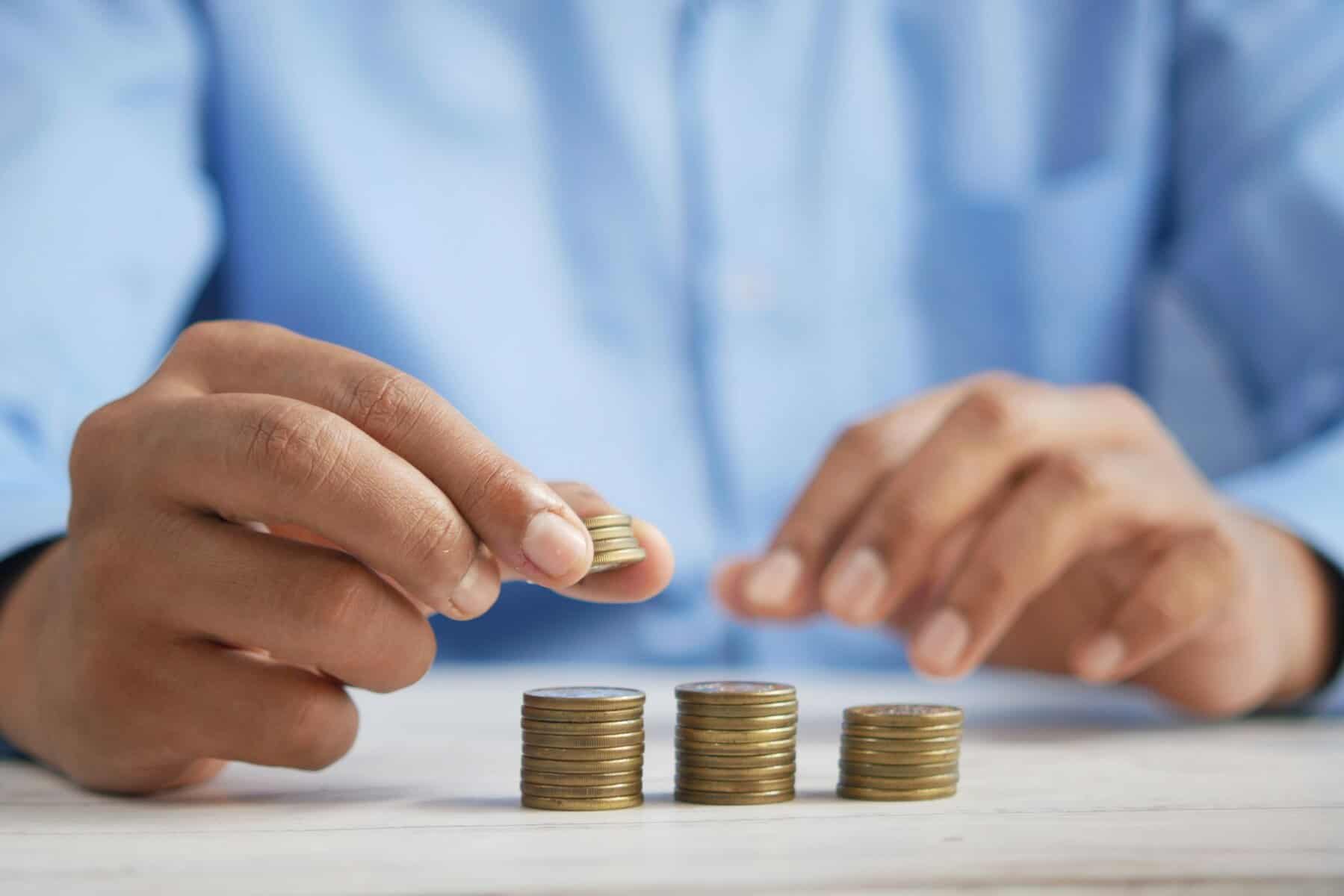 Man in blue dress shirt stacking coins.