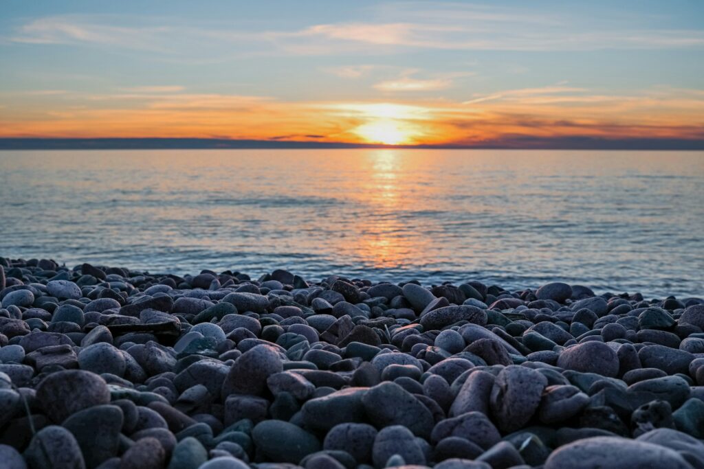 Catholic Sisters Make History: Returning boarding school land to tribe Sunset over Lake Superior with the rocky shore in the foreground.