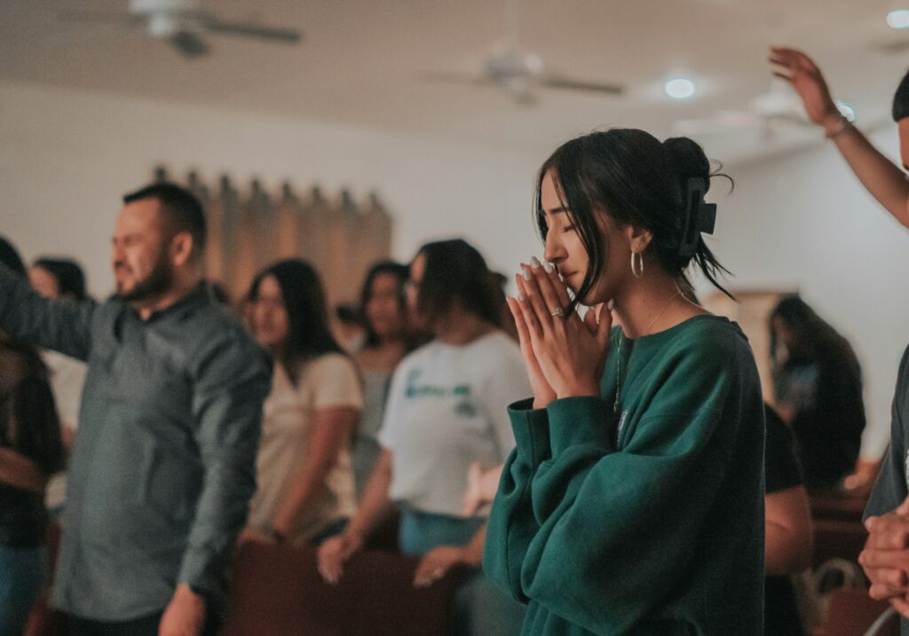 Asbury Revival and Beyond: Brown cites surging faith across generations A woman with hands in prayer, eyes closed, participating in a faith-based worship service.