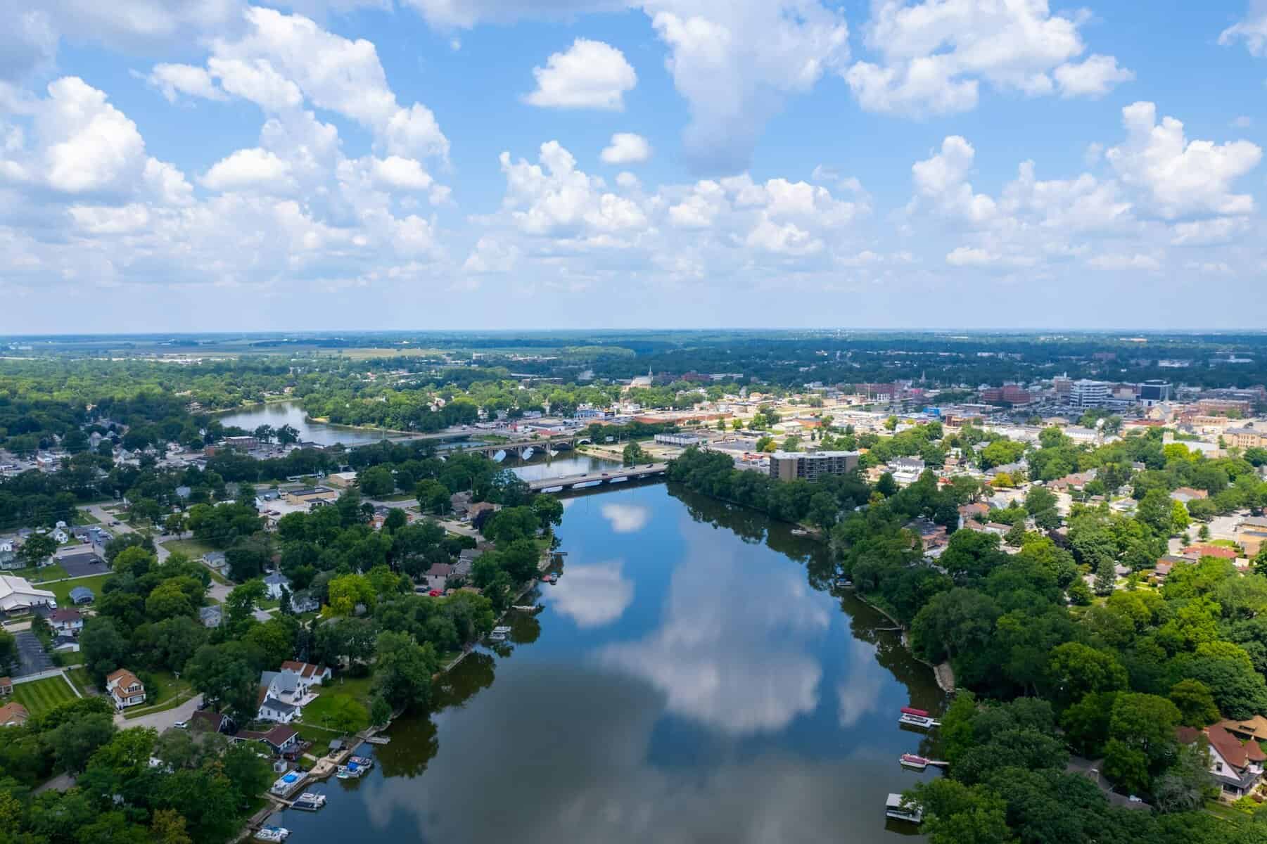 Areal view of a river and town in Illinois with puffy white clouds in a blue sky.