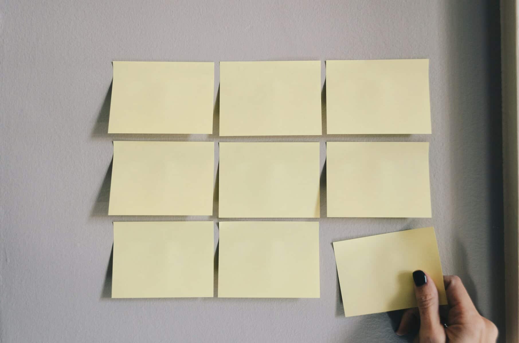 Rows of yellow sticky notes with a hand removing one.