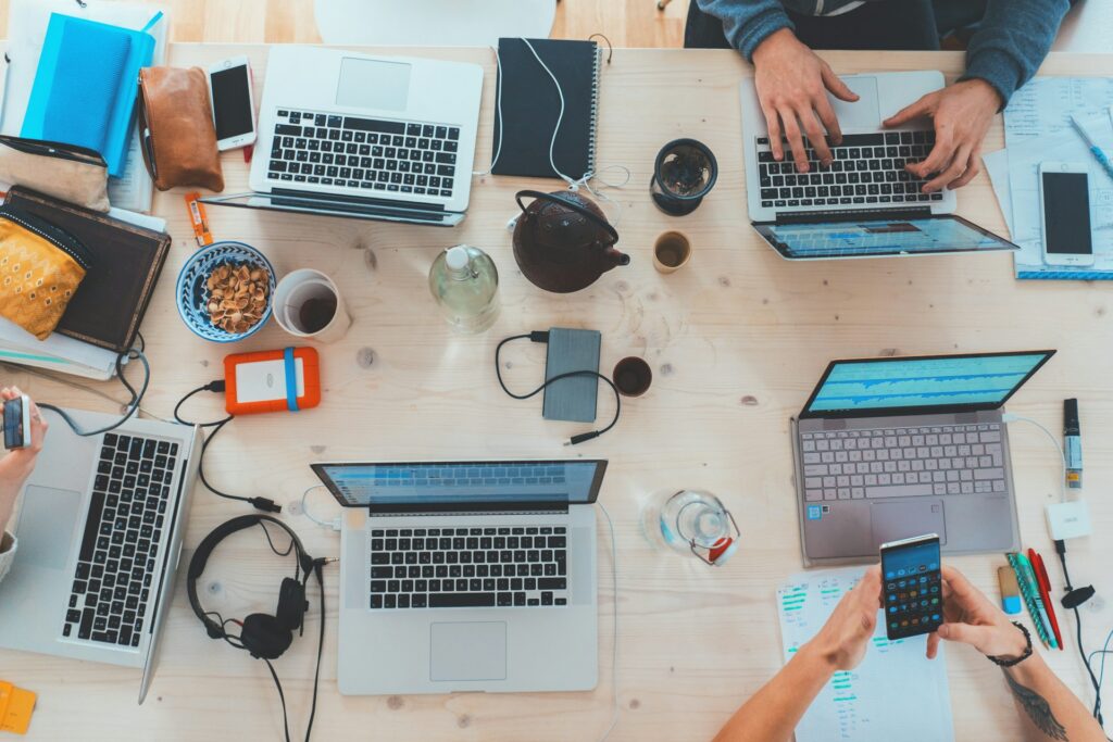 How Catholic digital identity is being rewritten by influencers Laptops on a table surrounded by coffee cups and people.