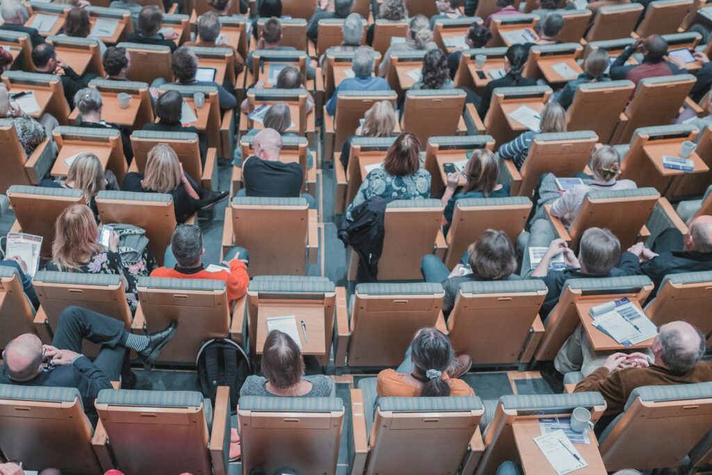 A lecture hall filled with students as seen from behind.