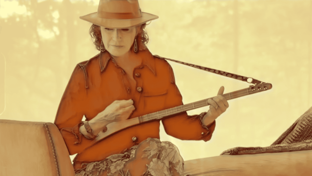 Amy Grant in western style dress playing the strumstick.