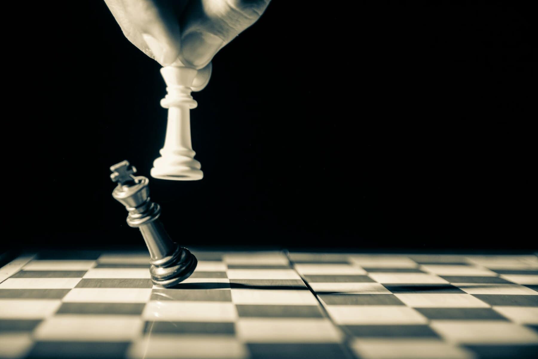 A chess piece being used to knock another one off the board.