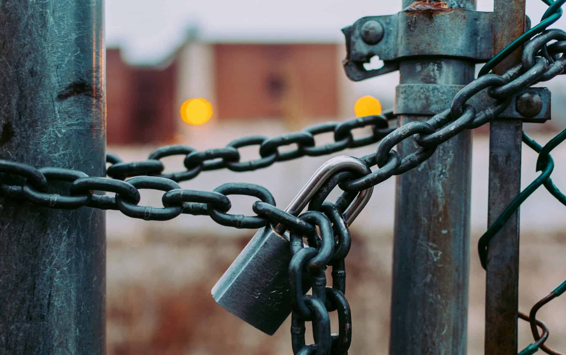 A chain and padlock on a chain link fence.