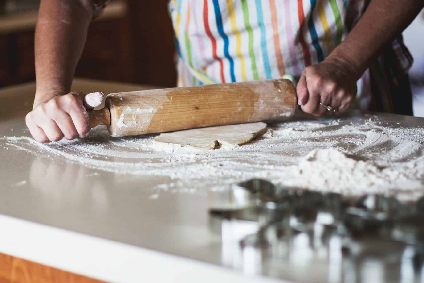 A woman's torso and hands shown using a rolling pin in baking.