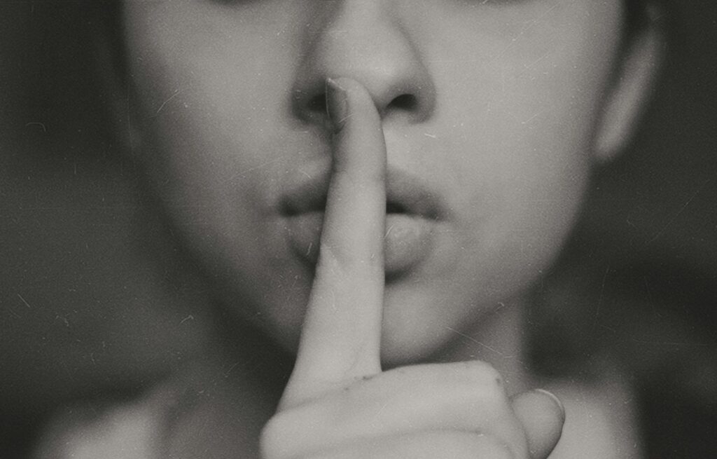A woman with her index finger at her lips.