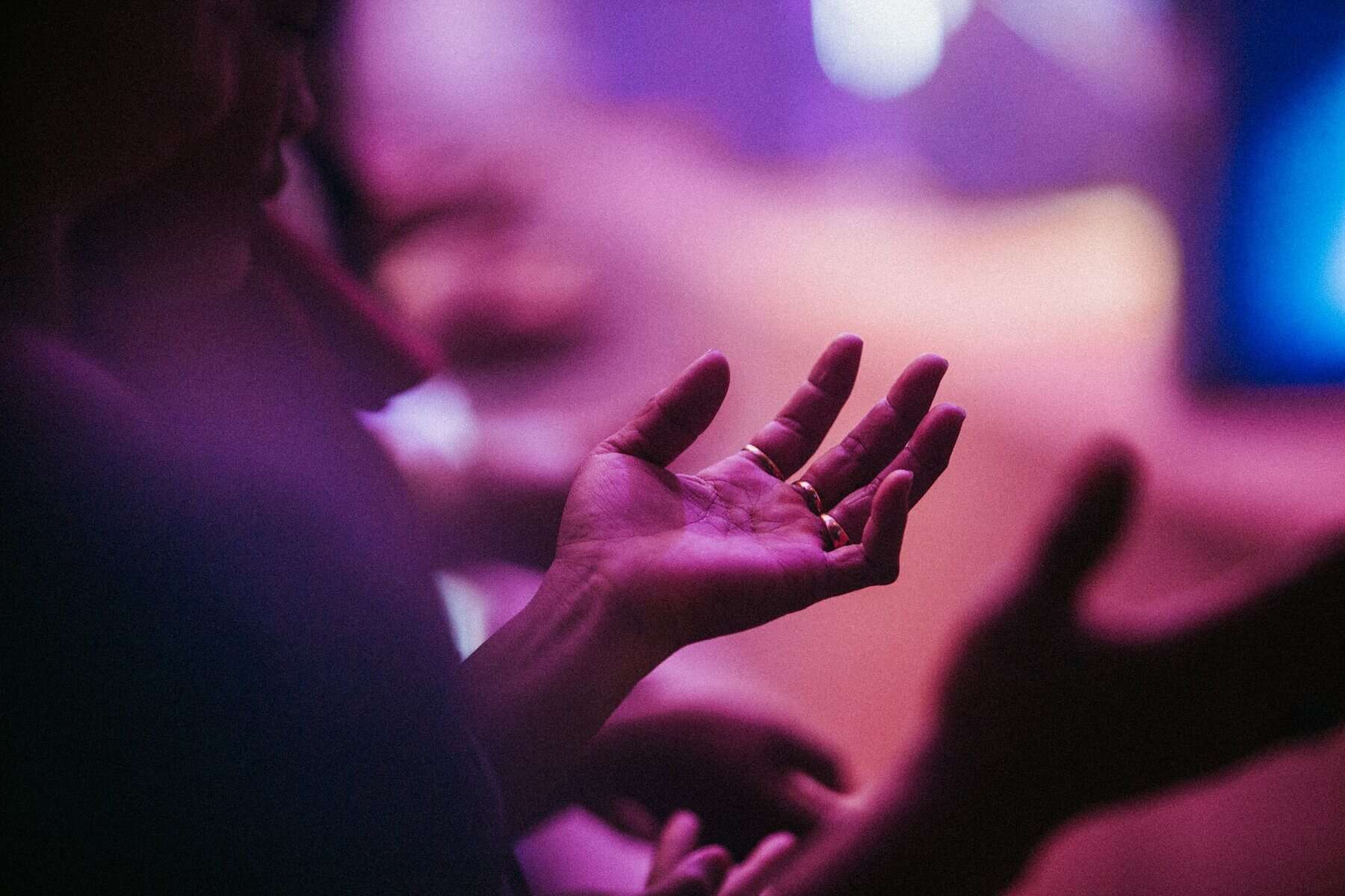 A person in a church service with palms up.