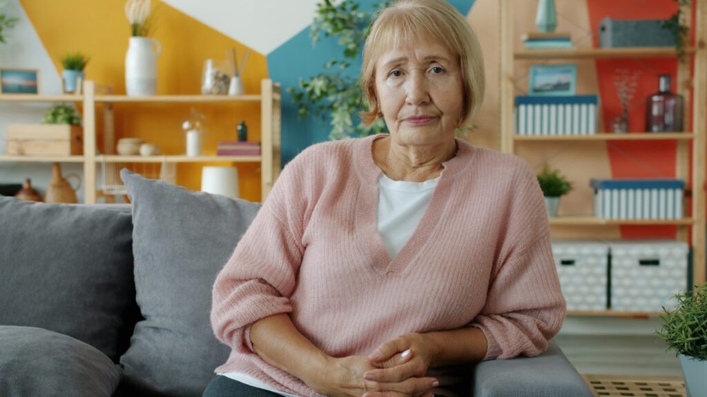 An older woman looks at the camera with an unimpressed affect.
