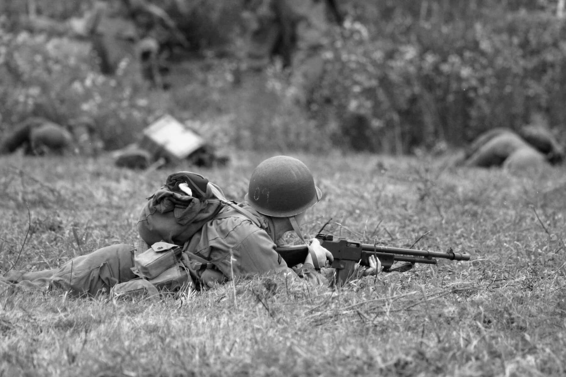 A soldier with a gun in tall grass.