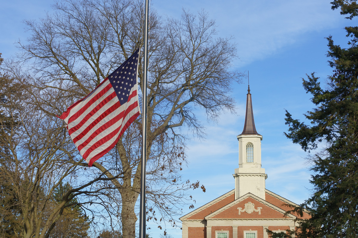 A United States flag at half mast in front of a church.