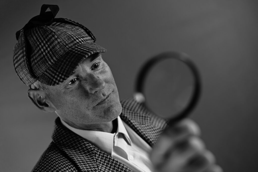 Crossroads Church Pastor Suspended: Shocking allegations trigger new probe A man dressed like Sherlock Holmes holds a magnifying glass.