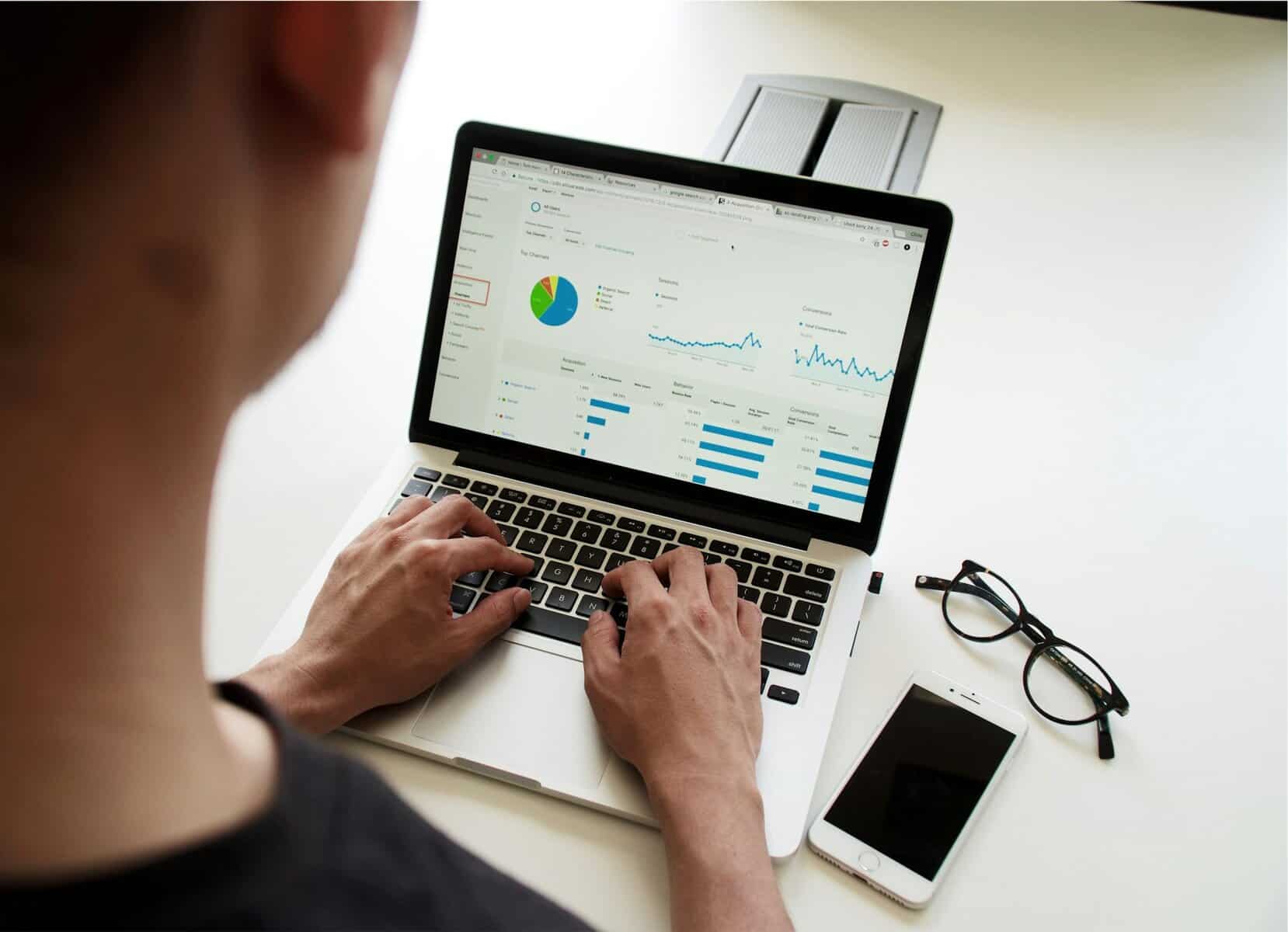 A person sits at a laptop displaying graphs.