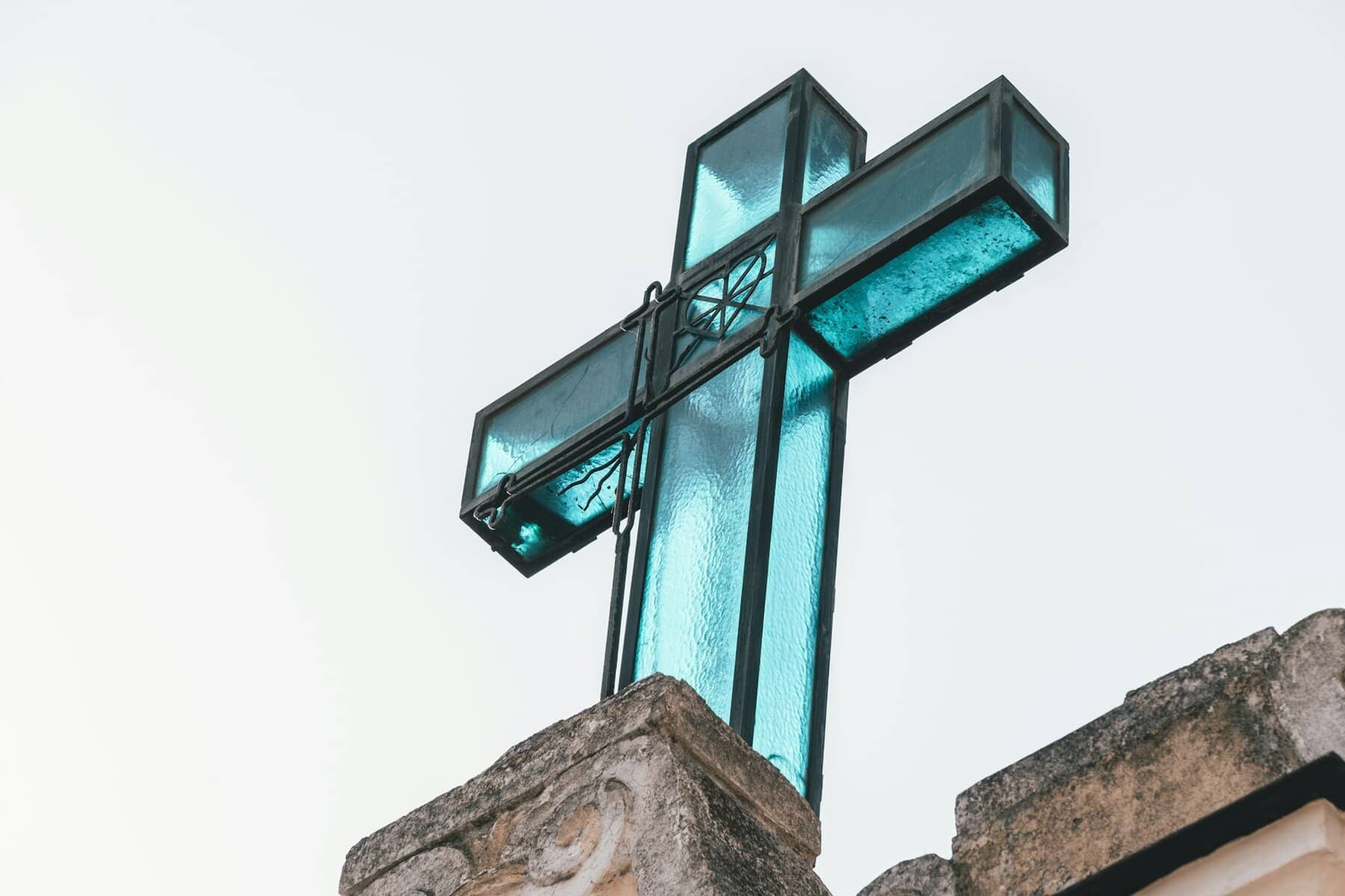 A blue glass cross with a black metal frame.