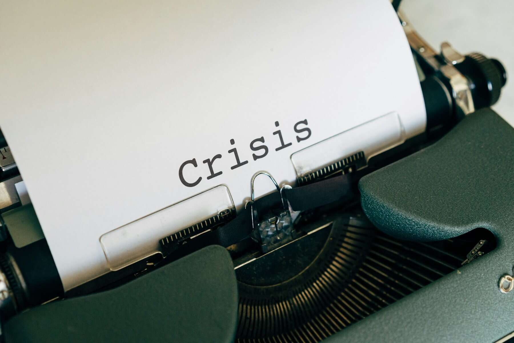 A typewriter with a piece of paper that says "Crisis".