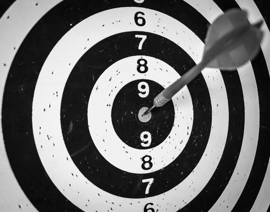 A black and white dart target with a dart in the center.