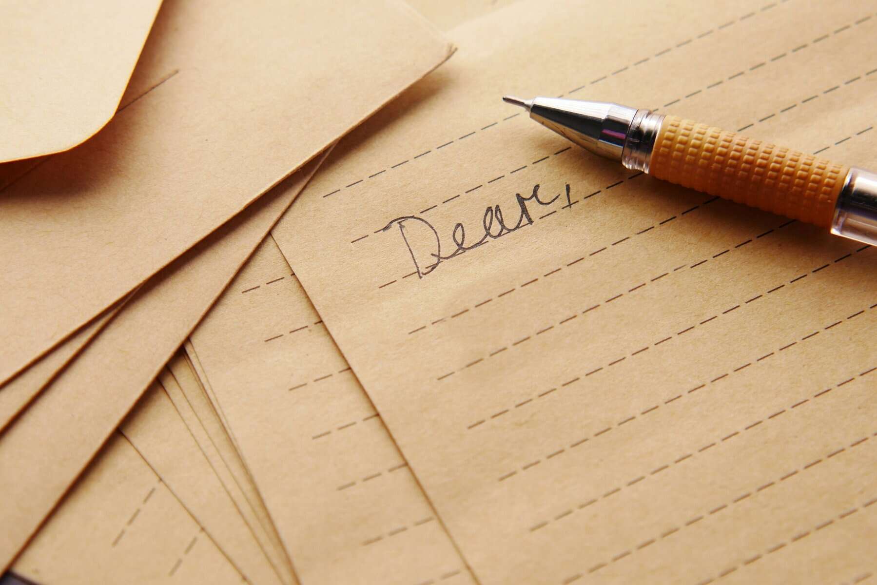 The beginning of a handwritten letter on tan paper.
